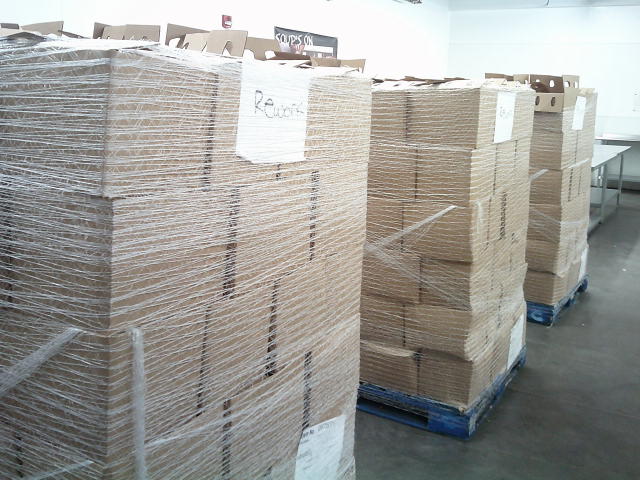 Multiple pallets of cardboard boxes wrapped in stretch wrap labeled with a piece of paper that says rework.