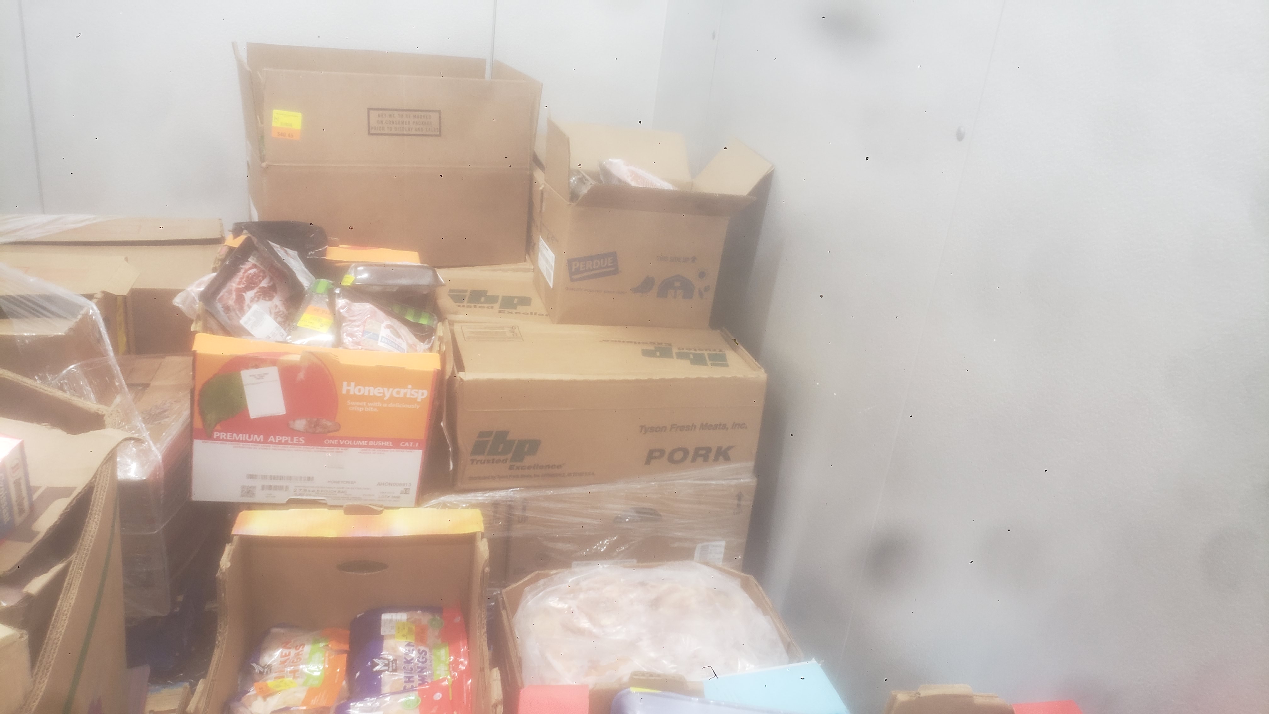 Assorted frozen items in cardboard boxes such as chicken wings, chicken thighs, and pork