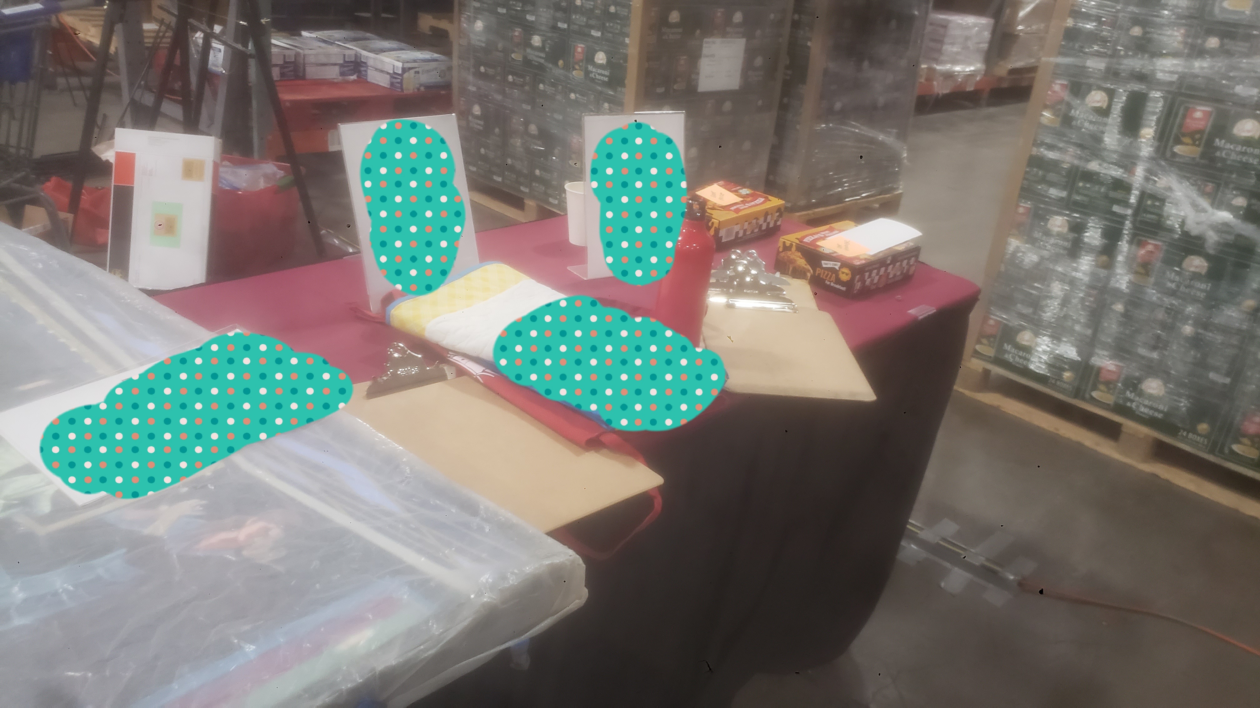 Silent auction items such as a blanket with the food bank logo on a table with signs.