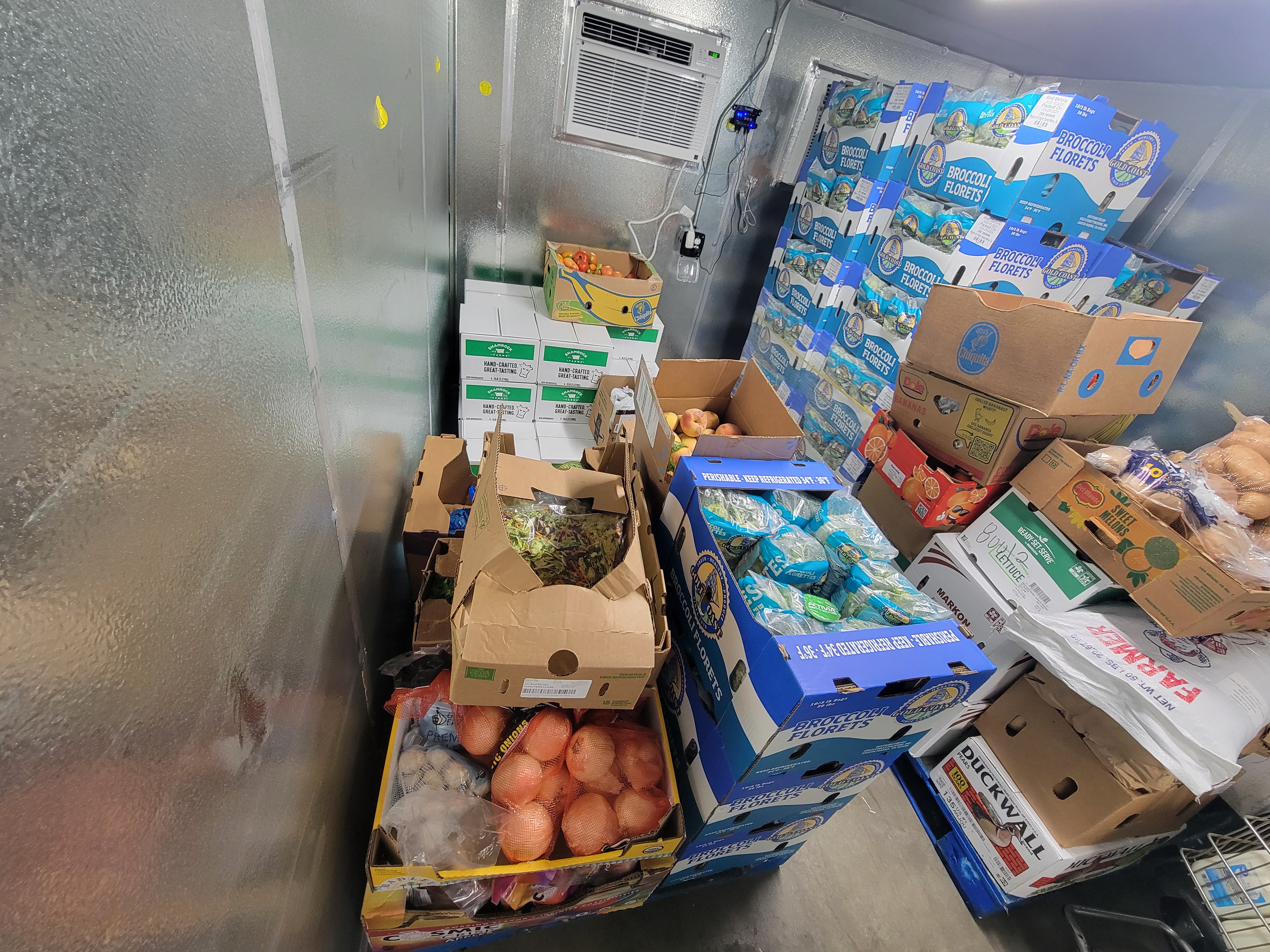 Boxes of produce and cottage cheese in a box fridge unit.
