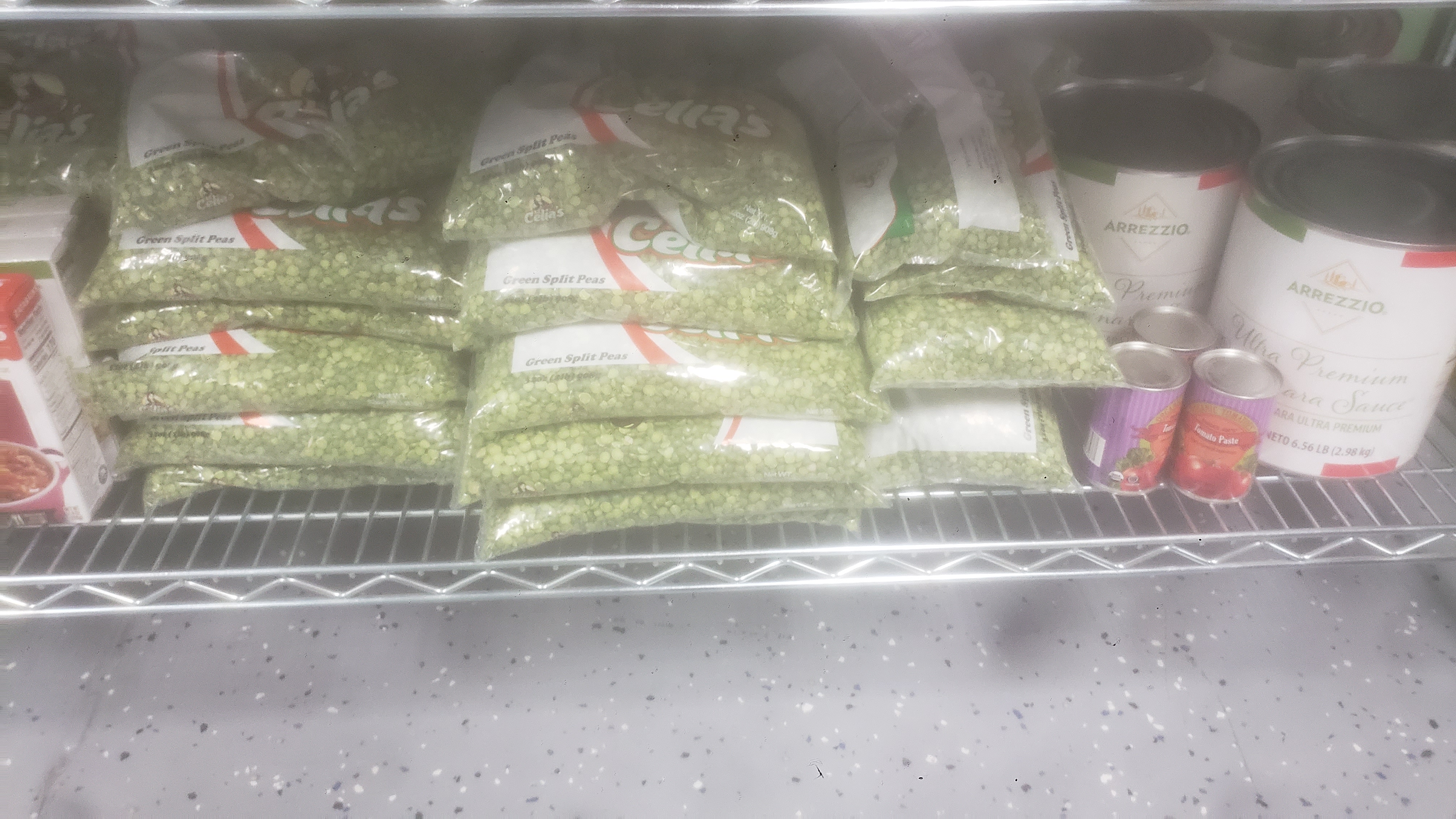 Bags of green split peas next to cans of tomato sauce and marina sauce.