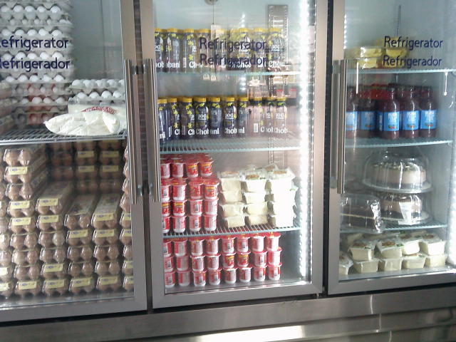 Fridge full of various foods such as eggs, yogurt drinks plus cups, cakes, and bottles of something.
