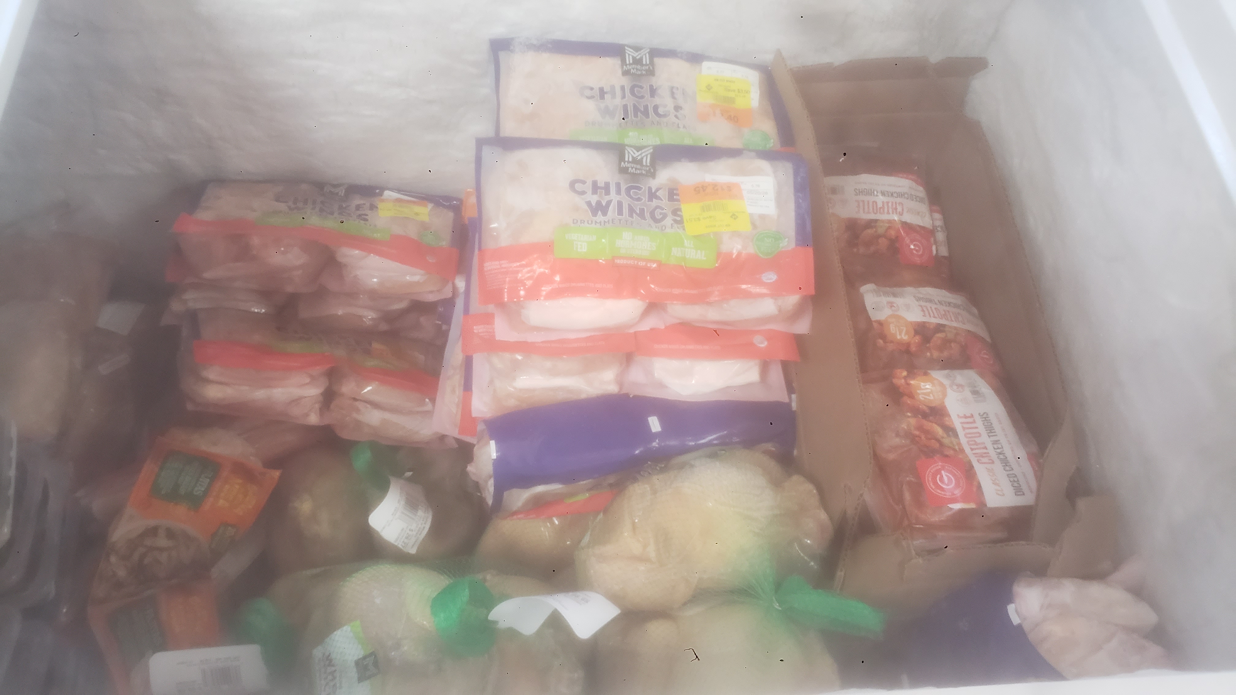 Various meats and cardboard box in a chest freezer.
