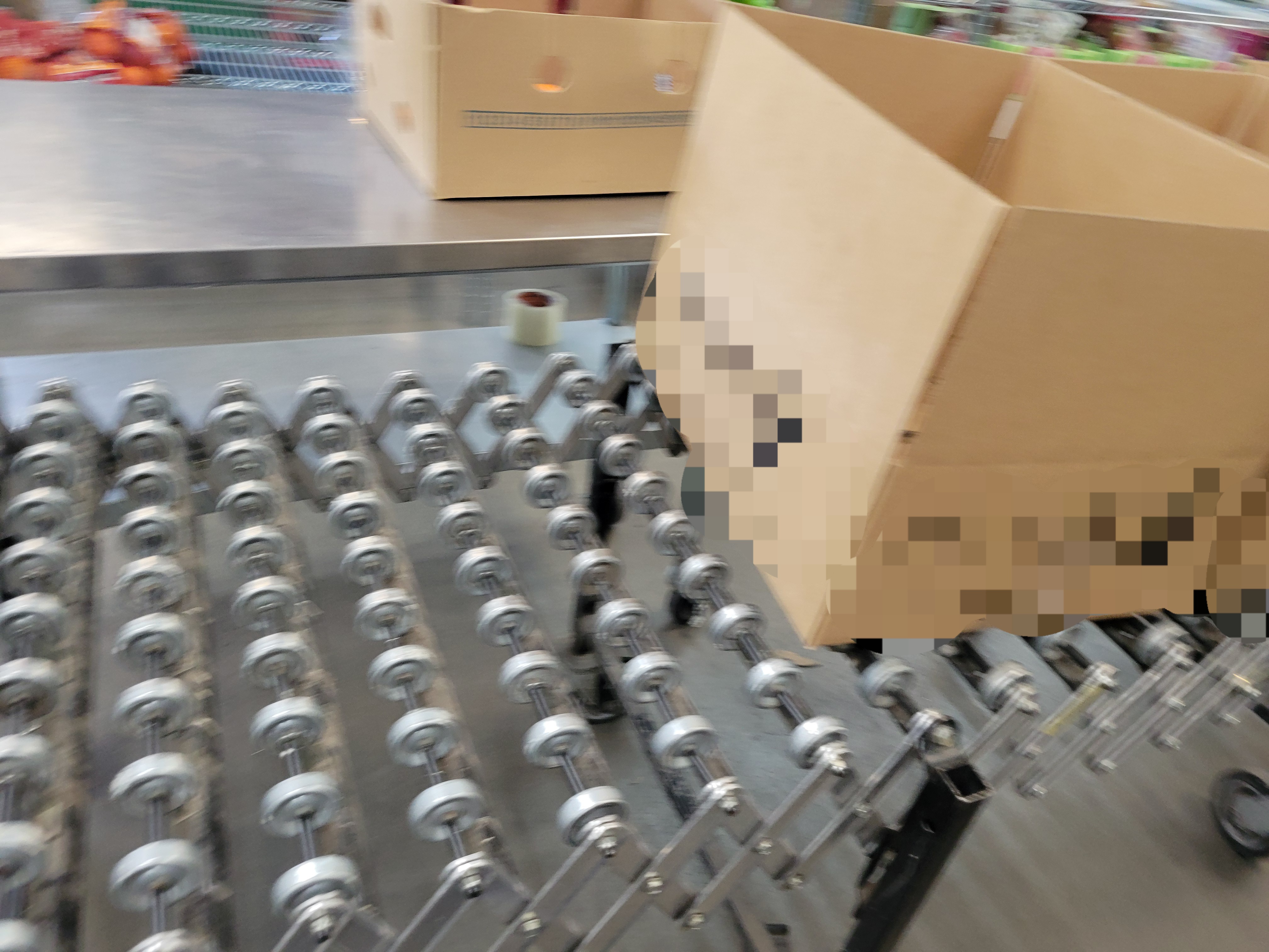 Boxes on a conveyor belt with table behind it.