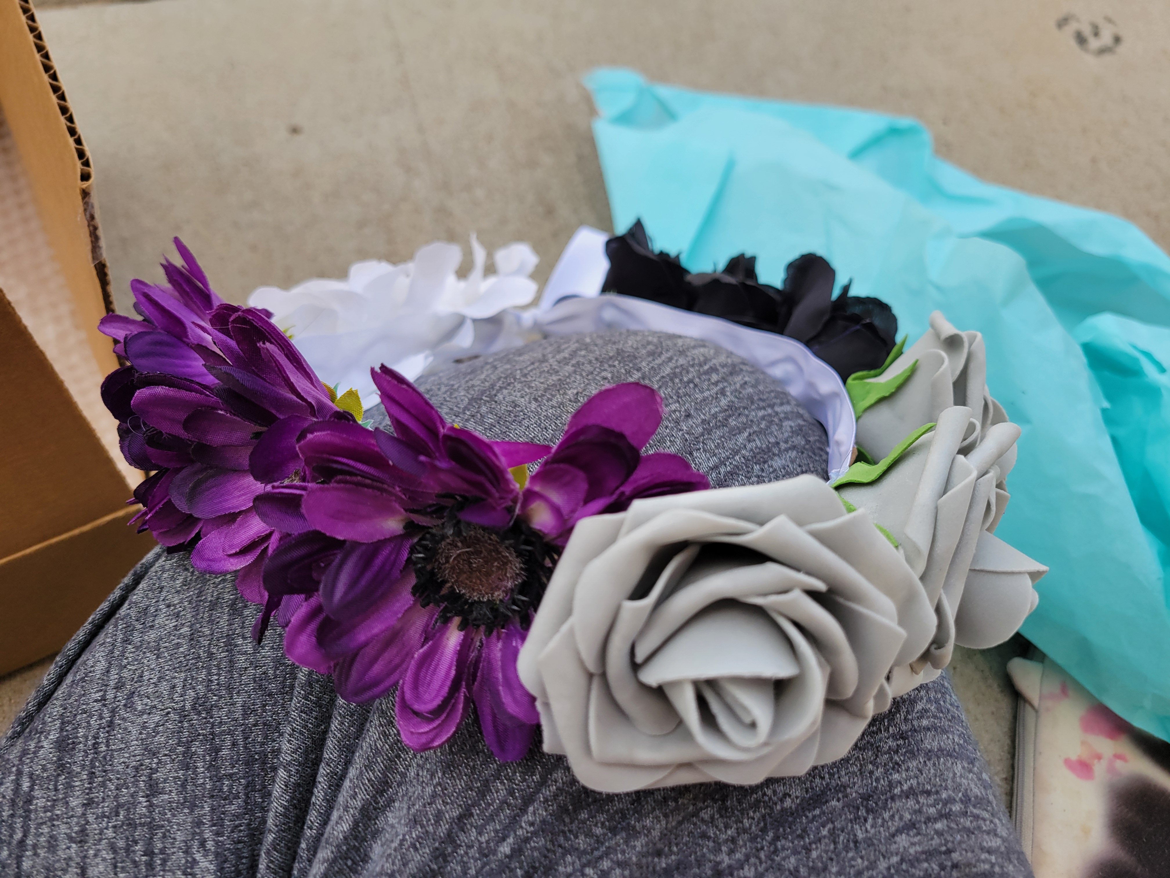 Different flowers on a flower crown in colors of purple, grey, white, and black.