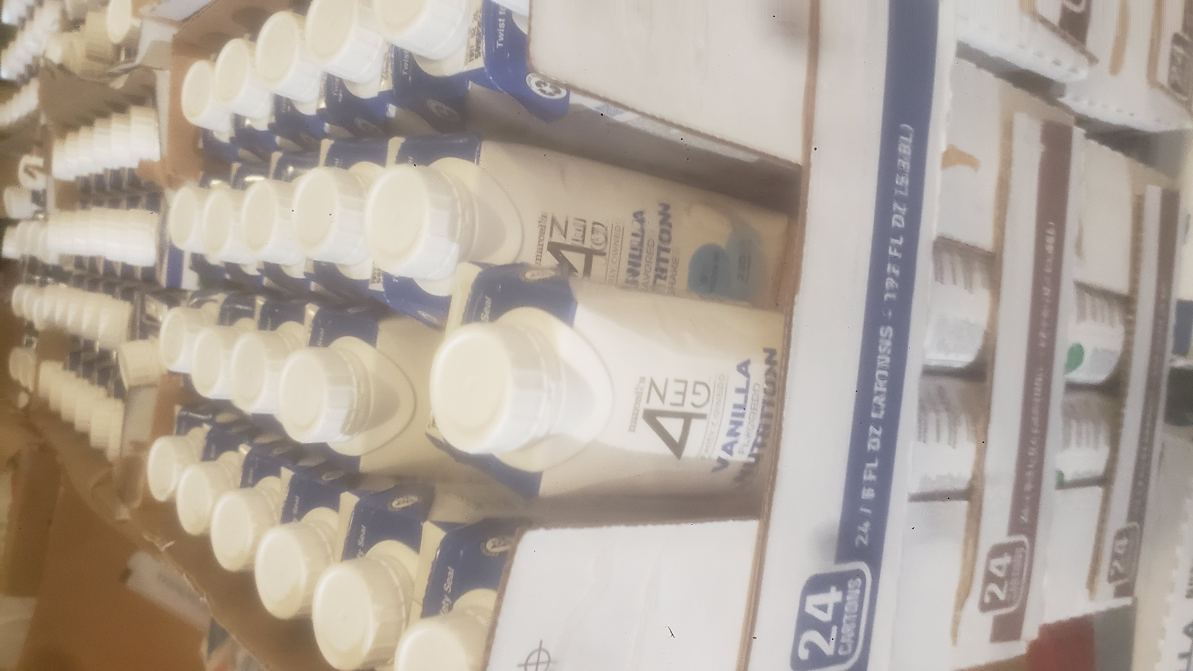Stacks of cardboard trays of cartons of vanilla nutrition shakes.
