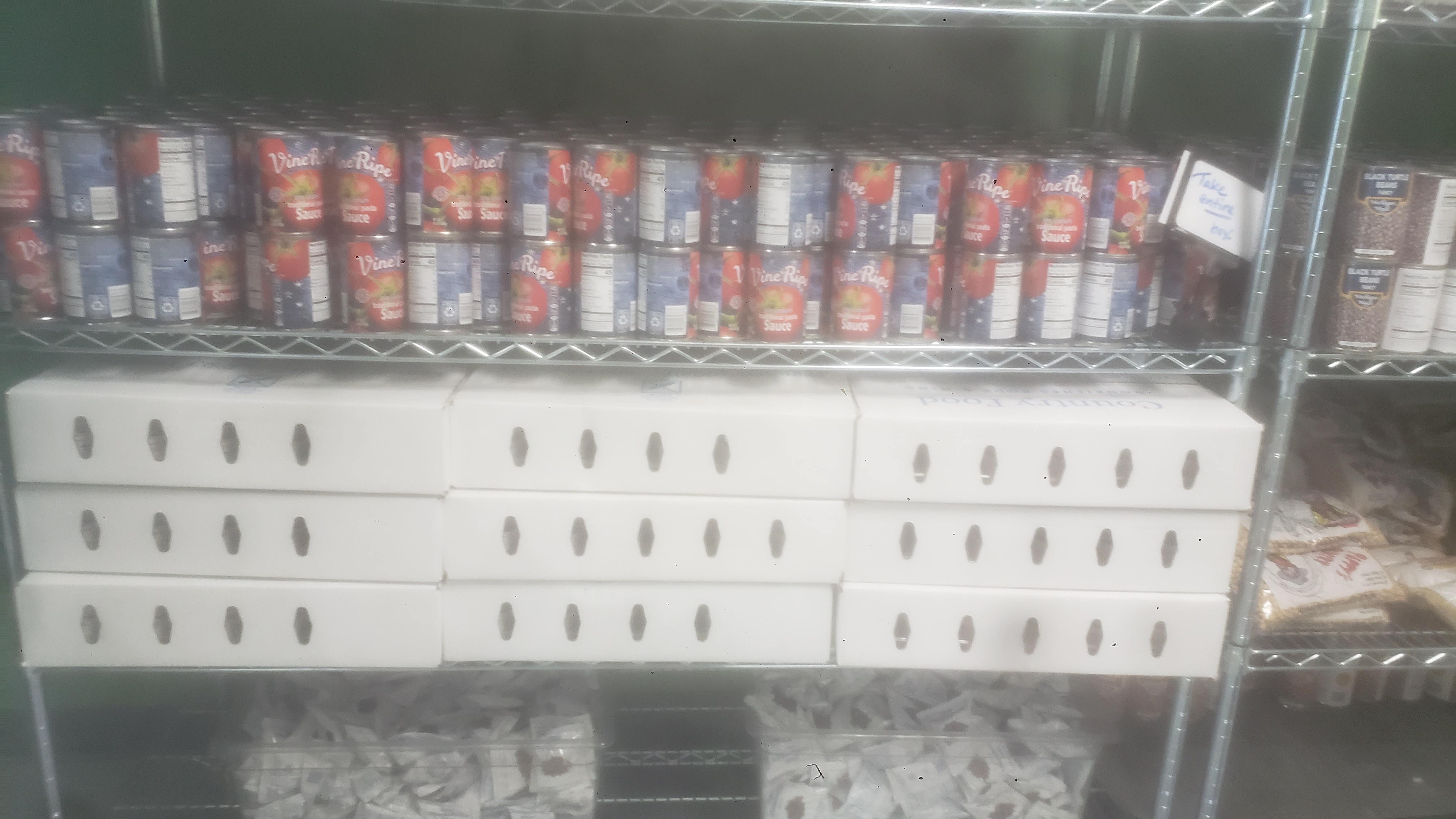 Cans of tomato sauce, boxes filled with cups of dutch apple, and packets of dried cranberries on a shelf
