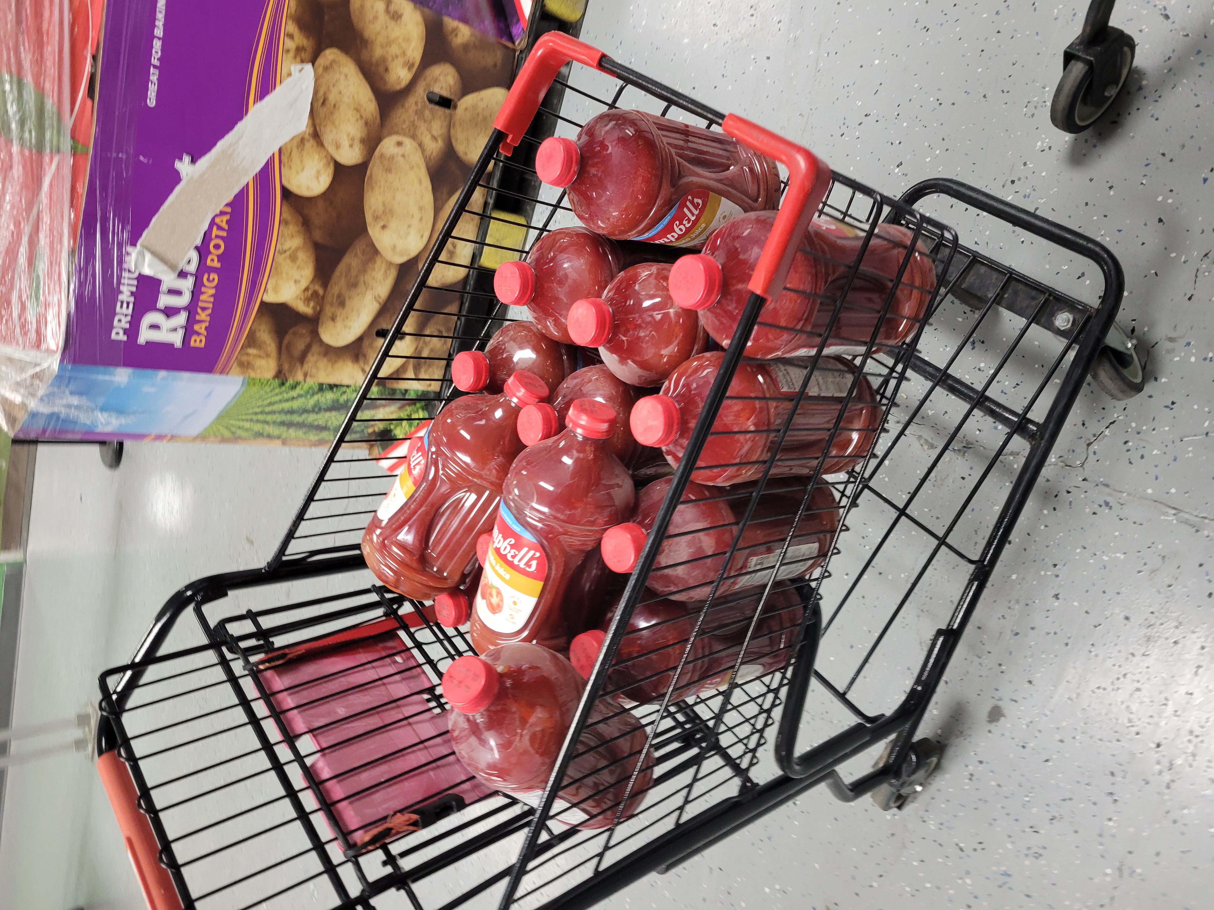 Gallons of tomato juice in a shopping cart.