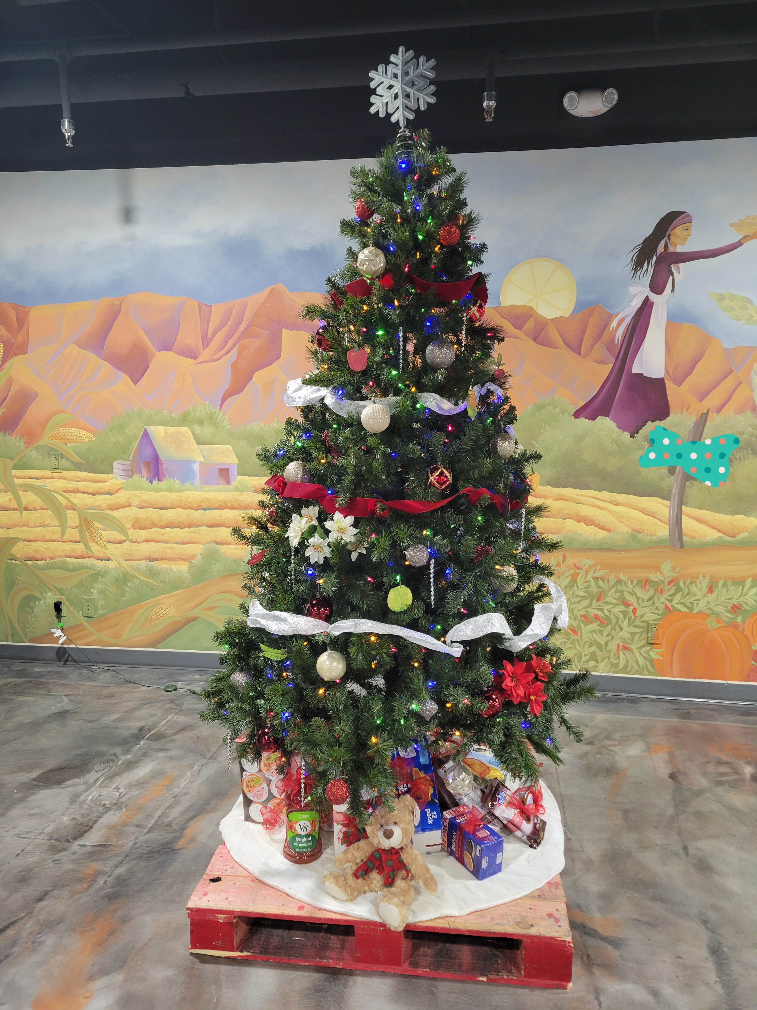 Christmas tree with food on the skirt on a pallet.