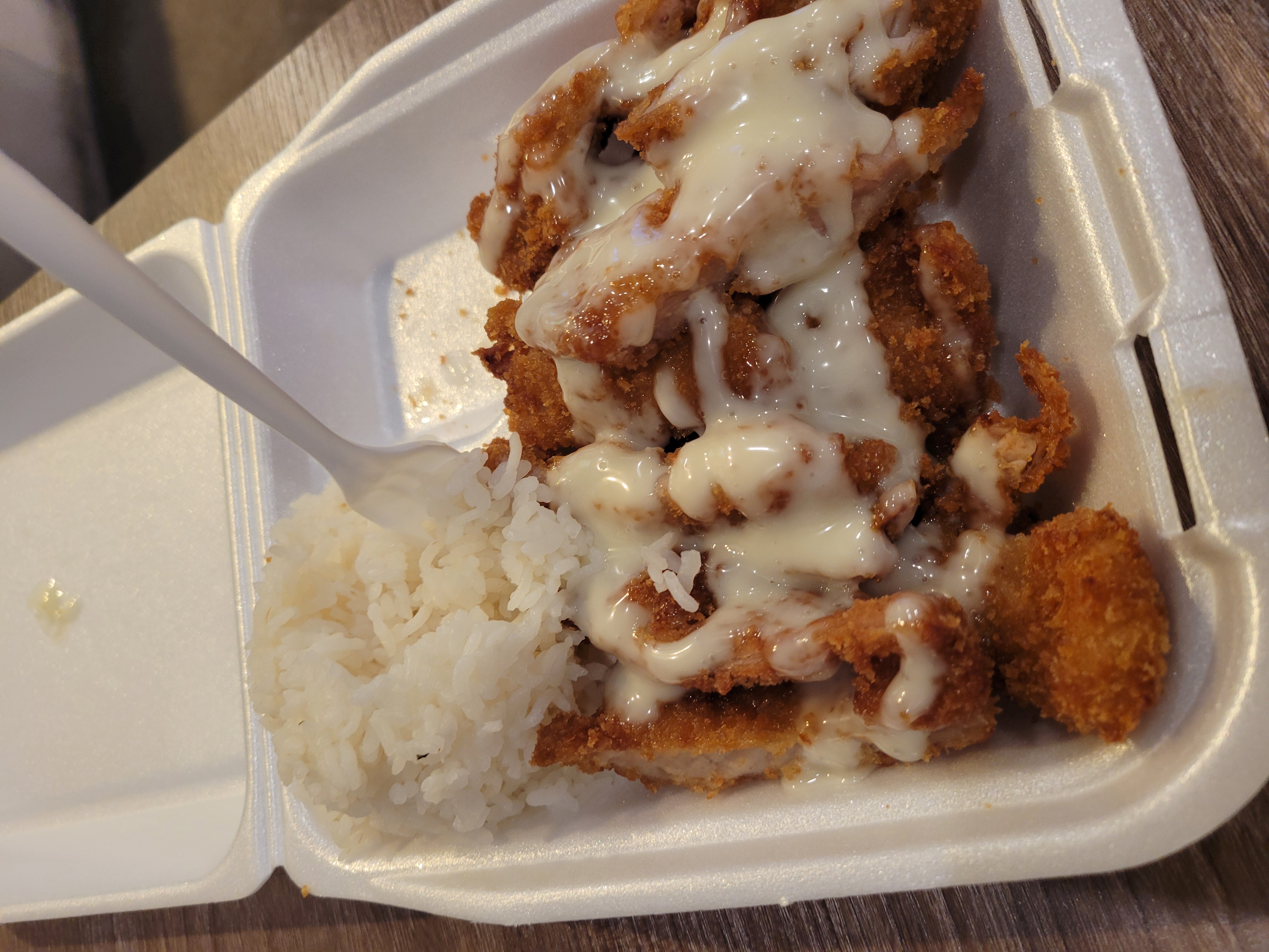 To go container full of chicken katsu with a scoop of rice and sauce.