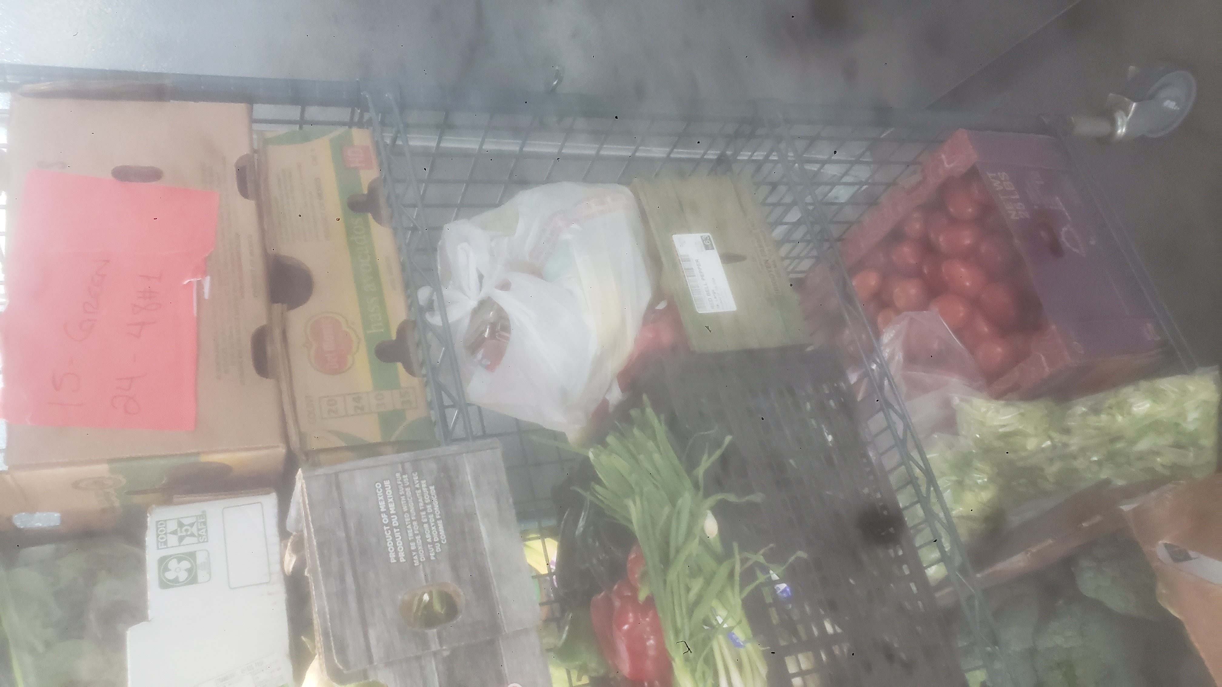 Assorted produce in bags, crate, and trays on racks of a cage shelf.
