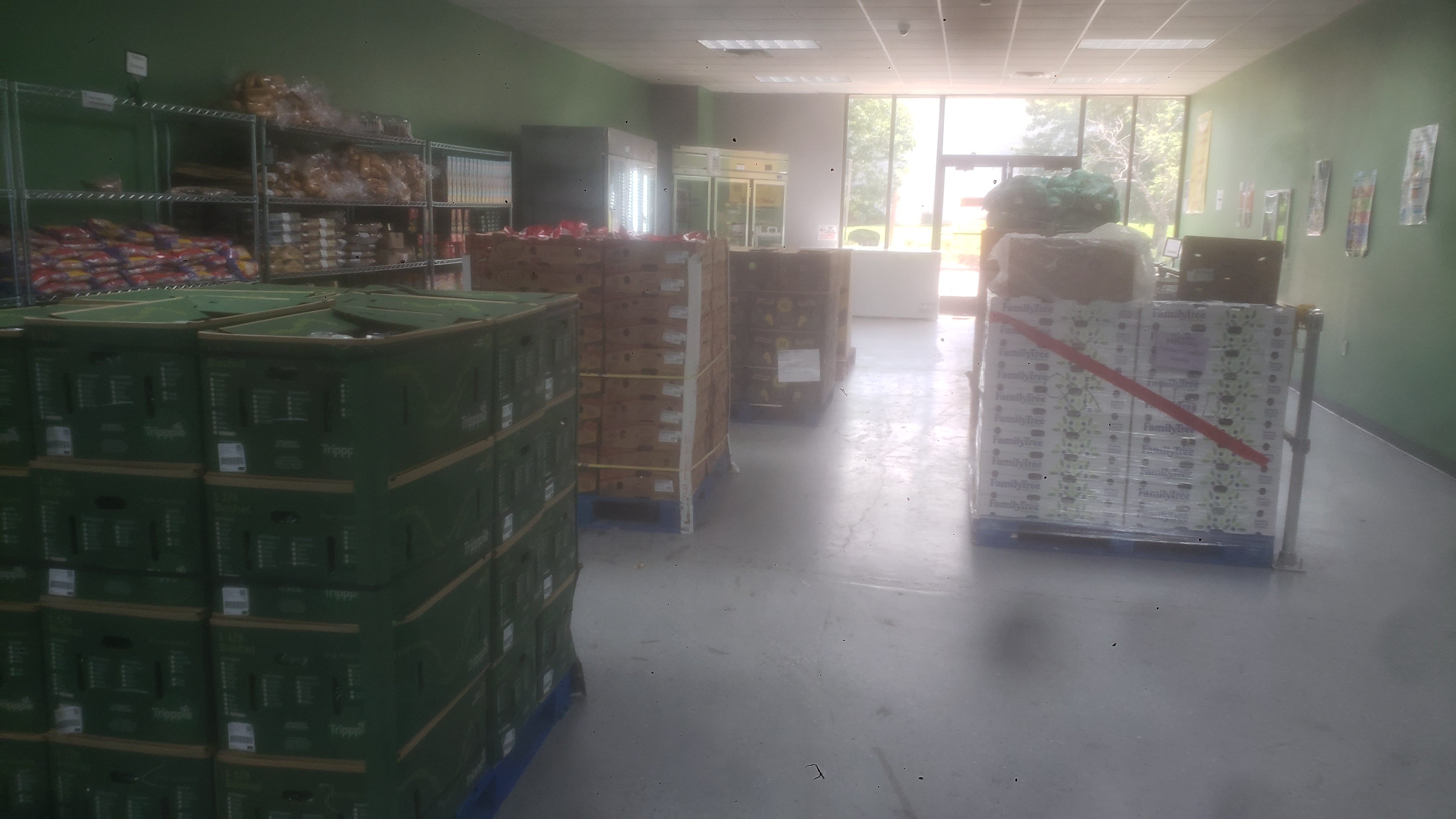 Pallets of produce, shelves, fridge, and freezer filled with food.
