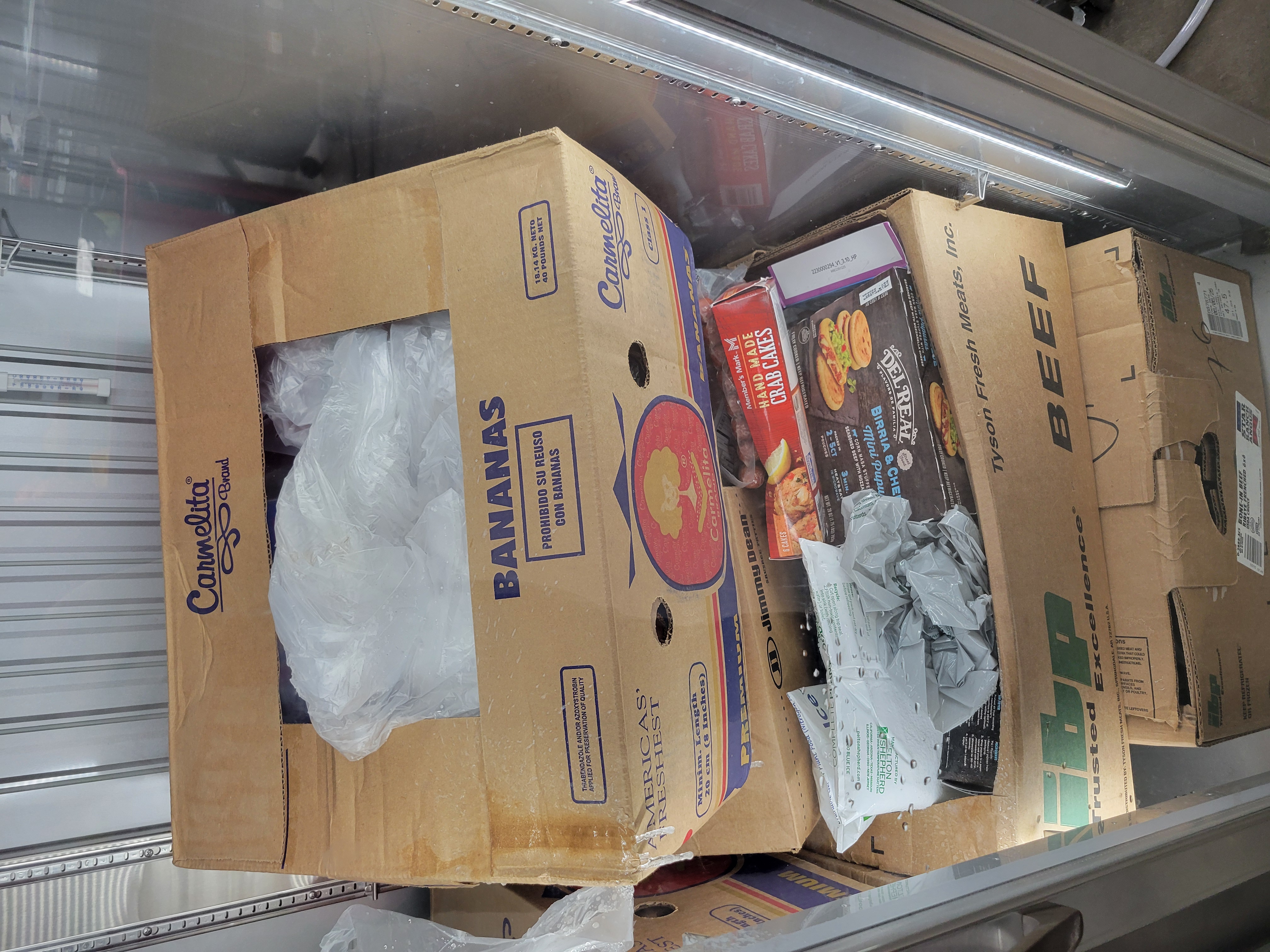 Cardboard boxes of food and gel packs in a fridge.