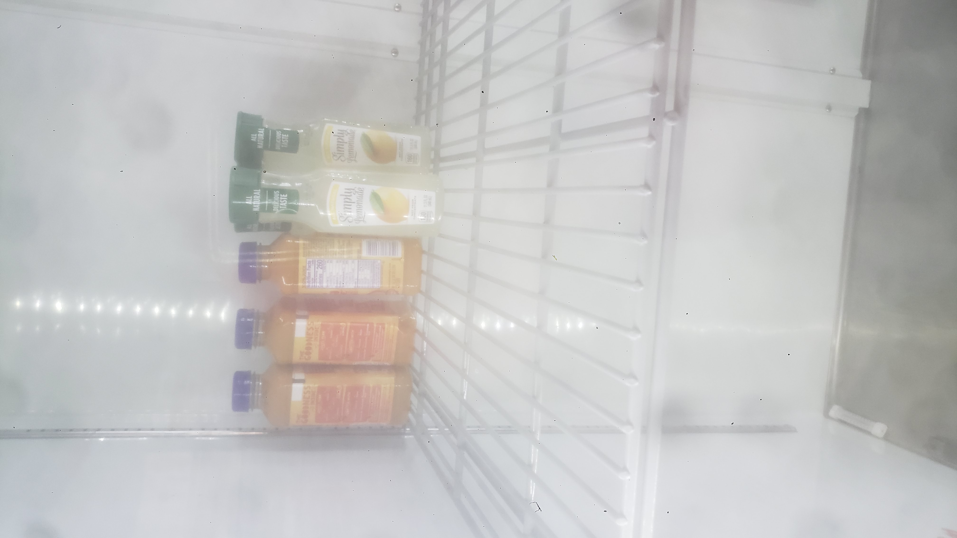 Bottles of lemonade and juice in a fridge..