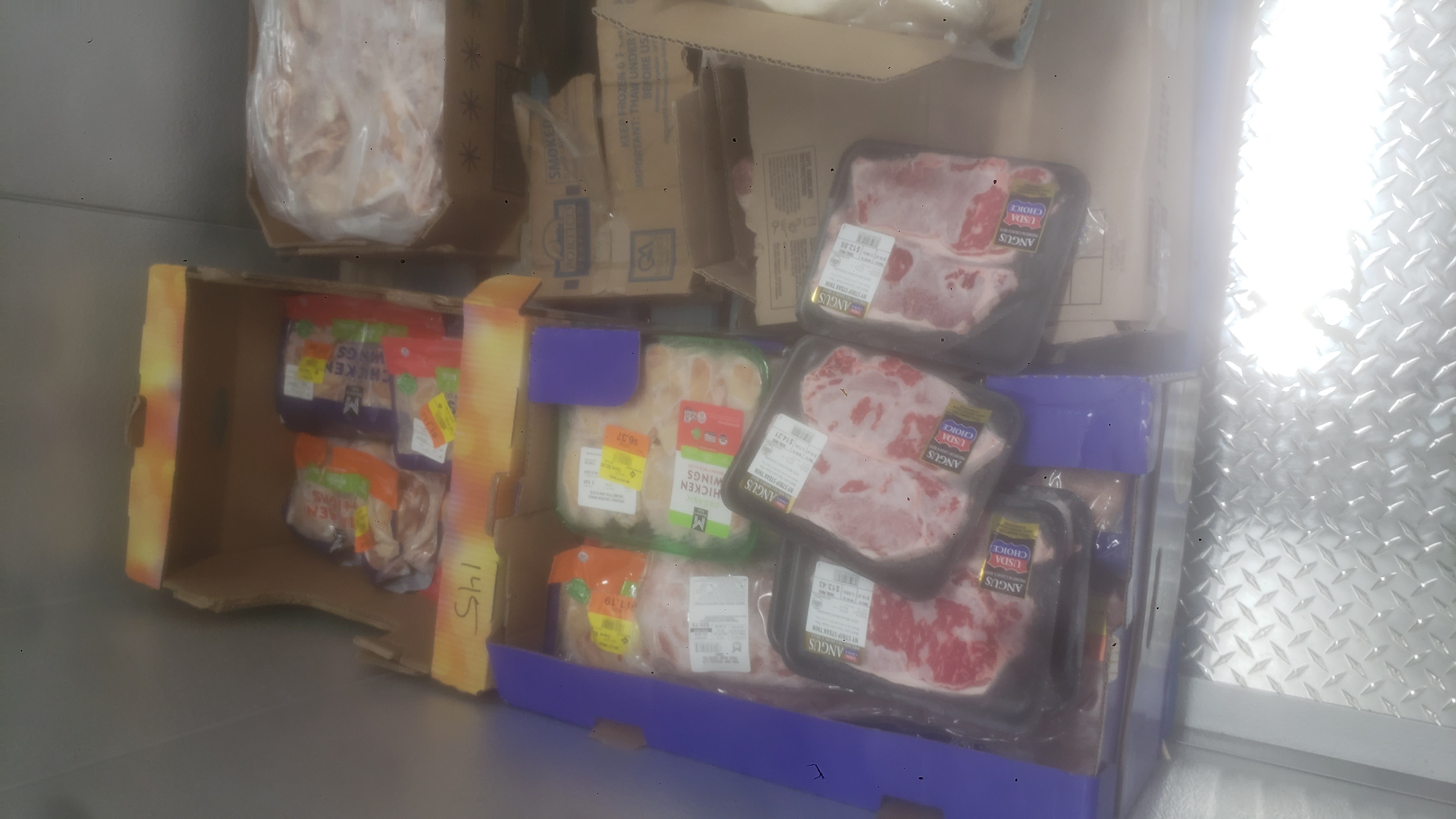 Various meats in boxes and trays on a pallet.
