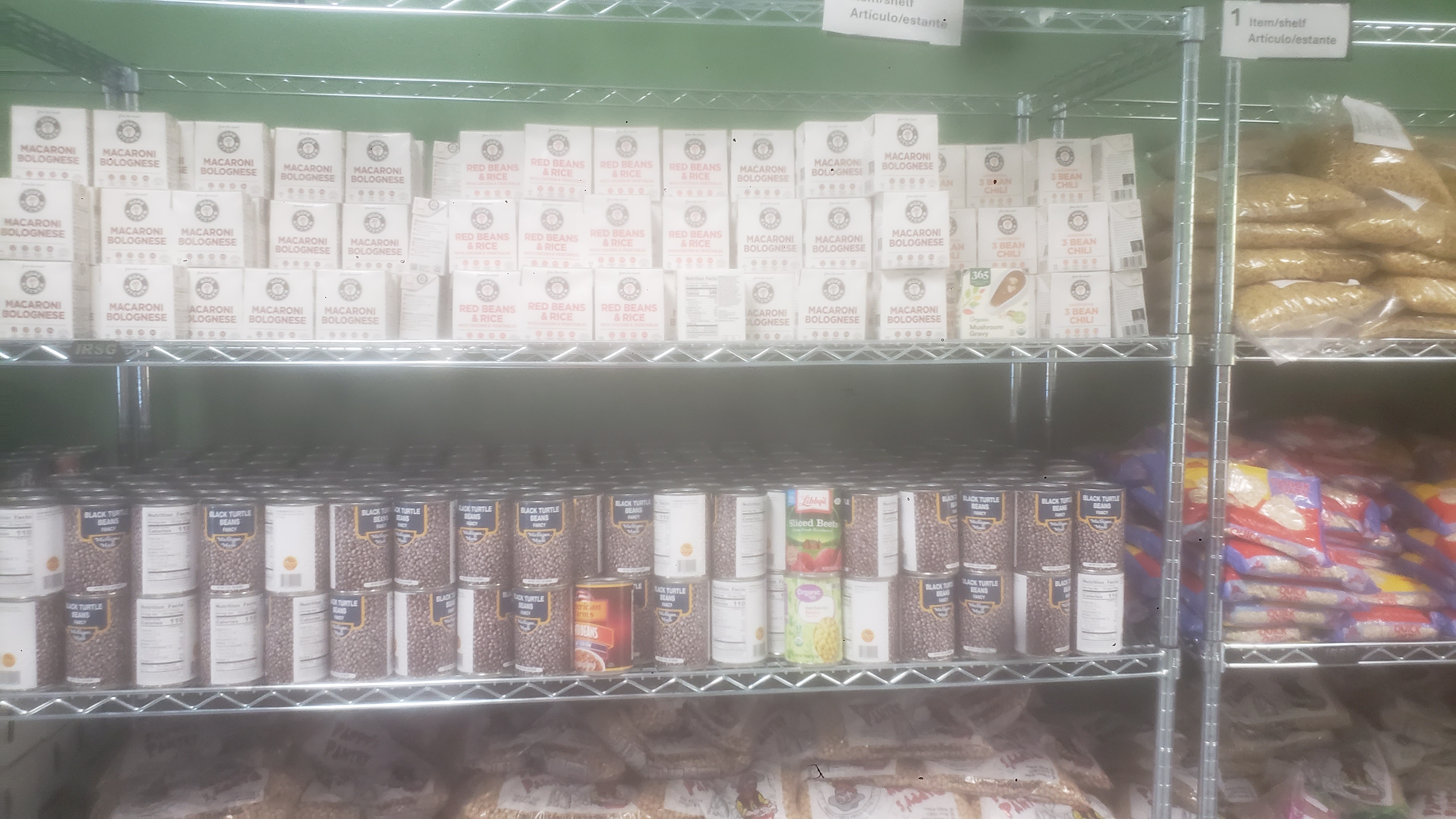 Cans of black turtle beans, ready to eat meals, and miscellaneous items on a shelf.
