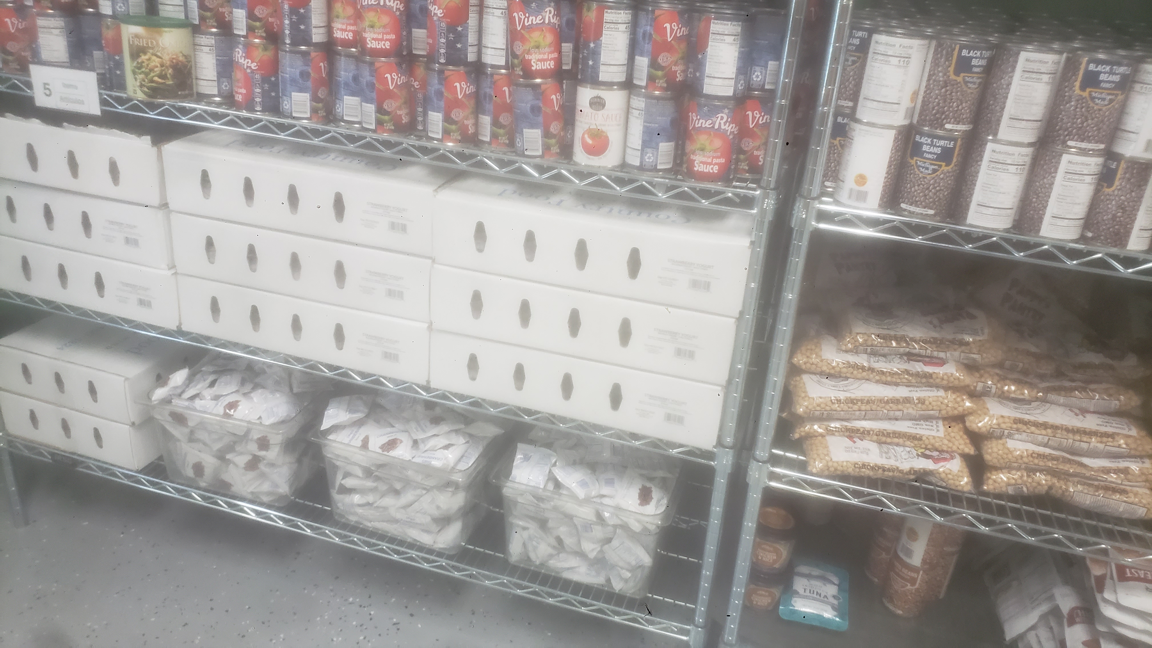 Cans of tomato sauce, packets of dried cranberries, and boxes of yogurt on a shelf.