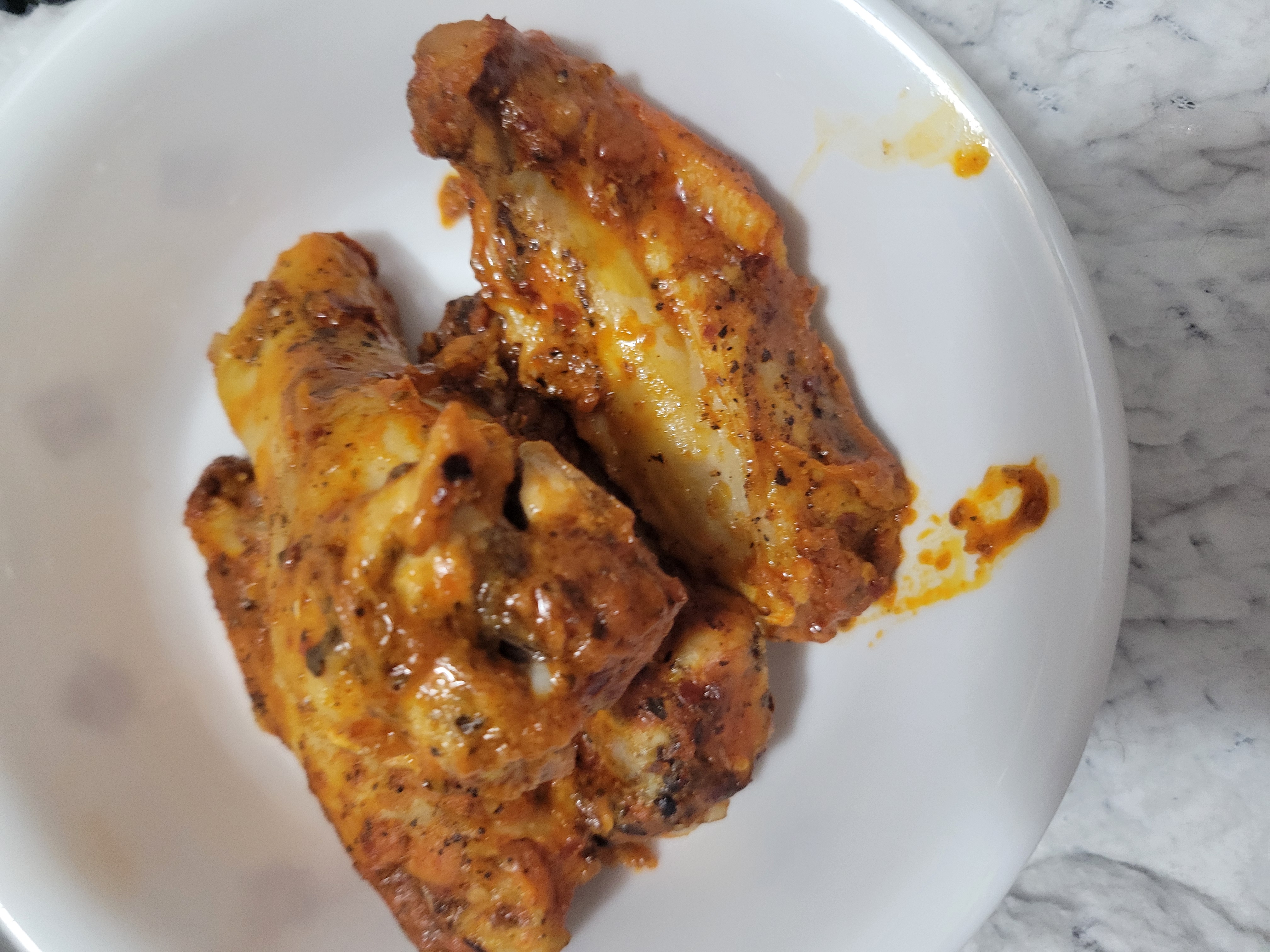 Chicken wings in a bowl on table.