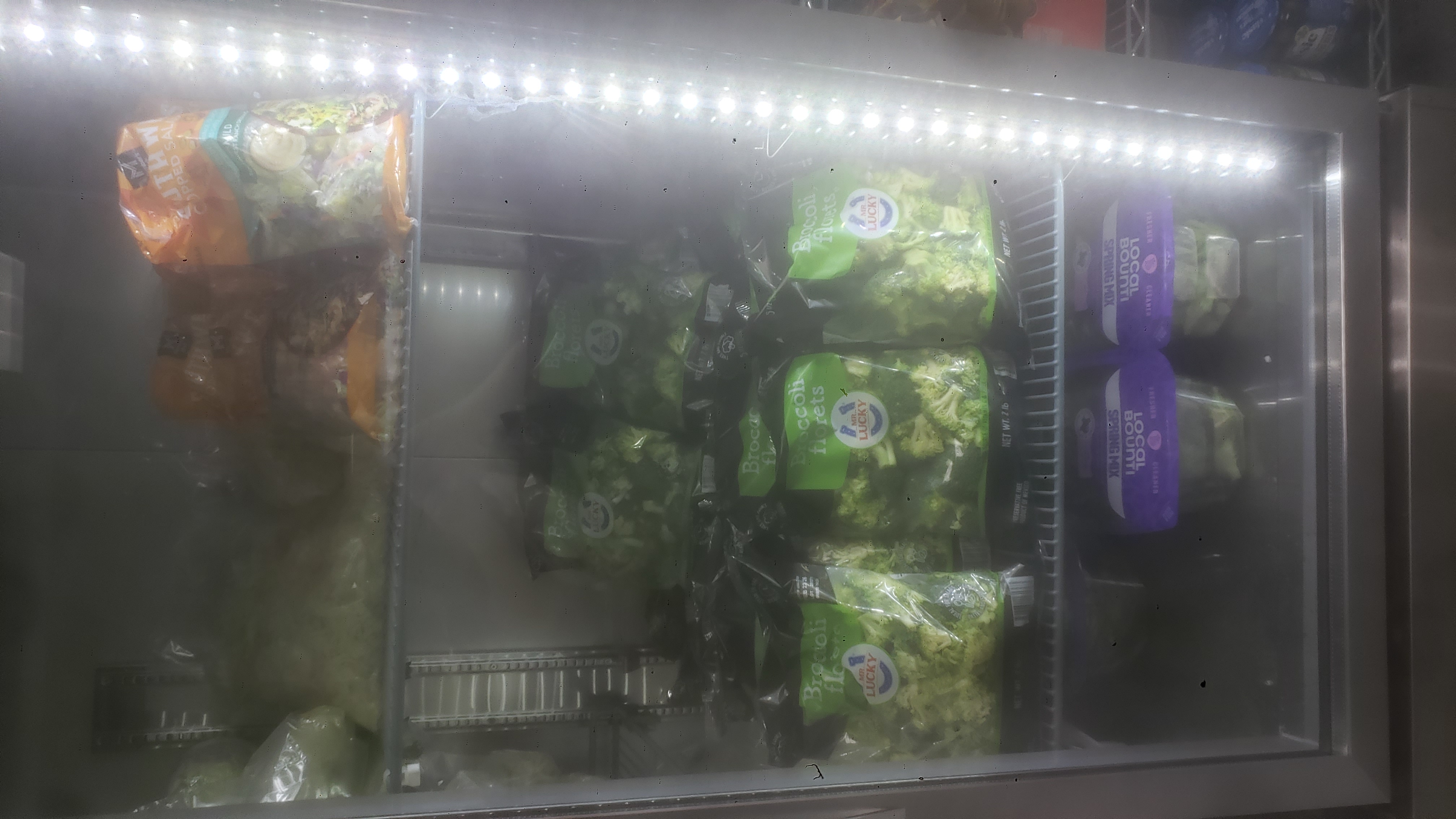 Bags of salad in a fridge.